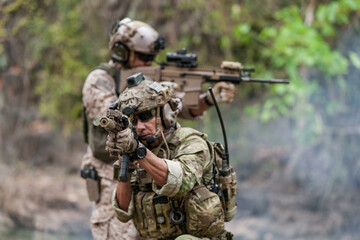 Soldiers in tactical gear aiming guns during a military exercise, showcasing teamwork and defense...