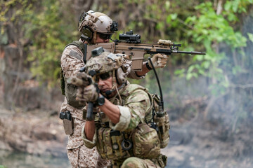 Soldiers in tactical gear aiming guns during a military exercise, showcasing teamwork and defense strategies.