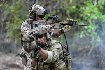 Soldiers in tactical gear aiming guns during a military exercise, showcasing teamwork and defense...