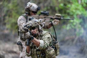 Soldiers in tactical gear aiming guns during a military exercise, showcasing teamwork and defense strategies.