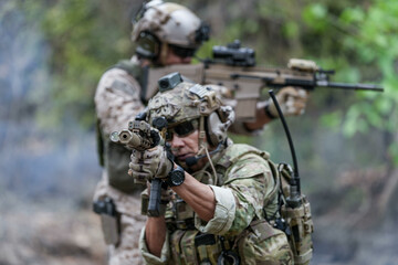 Fototapeta premium Soldiers in tactical gear aiming guns during a military exercise, showcasing teamwork and defense strategies.