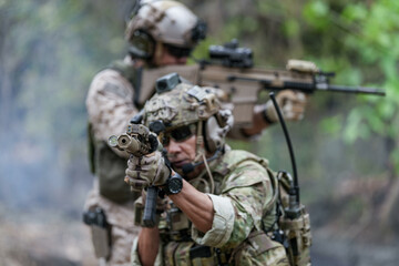 Fototapeta premium Soldiers in tactical gear aiming guns during a military exercise, showcasing teamwork and defense strategies.