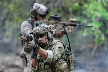 Fototapeta premium Soldiers in tactical gear aiming guns during a military exercise, showcasing teamwork and defense strategies.