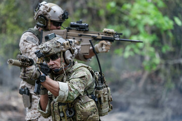 Fototapeta premium Soldiers in tactical gear aiming guns during a military exercise, showcasing teamwork and defense strategies.