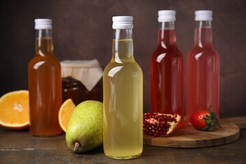 Delicious kombucha in glass bottles, jar and fresh fruits on wooden table