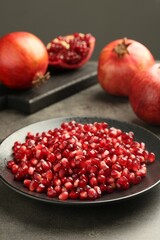Ripe juicy pomegranate grains on grey table
