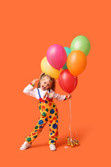 Fototapeta na wymiar Playful little girl in clown costume with balloons on orange background