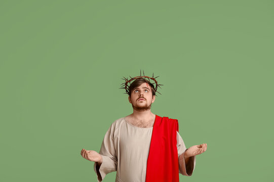 Man in Jesus robe and crown of thorns with blood, outstretching hands on green background - Powered by Adobe