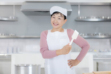 笑顔で料理道具を持つ中高年女性