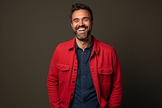 Portrait of a happy casual man laughing against a dark background.