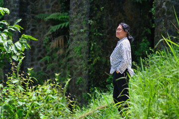 Naklejka na ściany i meble Woman standing alone in the middle of the bush admiring the beauty of nature