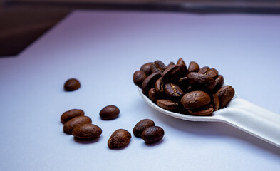 coffee beans over spoon setting on table background.