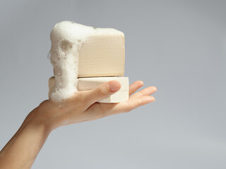 female women washing her hand with soap on grei gradient background. laundry soap in hand