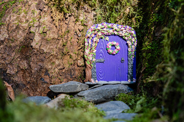 small purple door made of polymer clay on in nature like a fairy house close up
