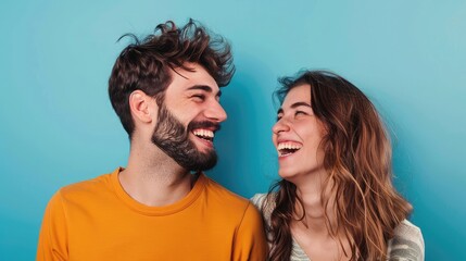 Isolated against a blue background, a young, attractive guy and lady are wondering and laughing at each other,Intimate moment of a smiling young couple in an indoor setting depicts modern love
