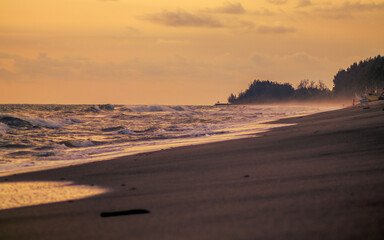 Empty beach landscape with silhouette of trees and building in the distance