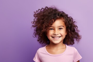 Portrait of a smiling little girl with curly hair against purple background