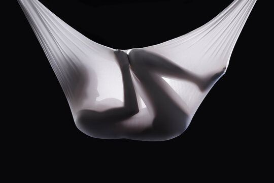 Person, fabric and wrapped naked in studio, abstract and creative art on black background. Woman, girl and material for ethereal or phantom ghost, bare and nude in sheet for fetus illusion in cloth