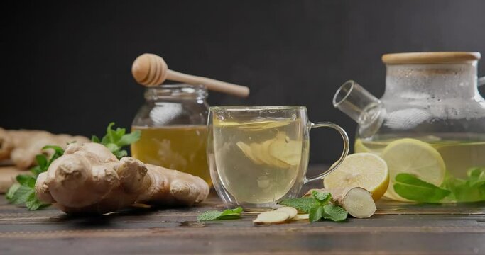sliced ginger root pieces falls into cup with hot steaming organic herbal tea