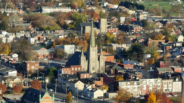 Chapel of historic church among row houses in urban USA city during autumn. Aerial parallax.