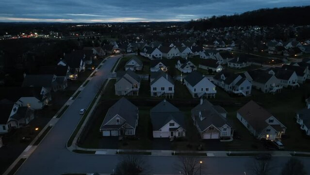 Aerial truck shot of dark neighborhood at night. Development with town lights in background.