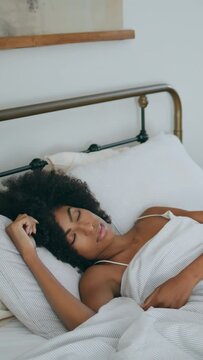 Curly woman sleeping bed at morning. Black skin lady napping home laying pillow