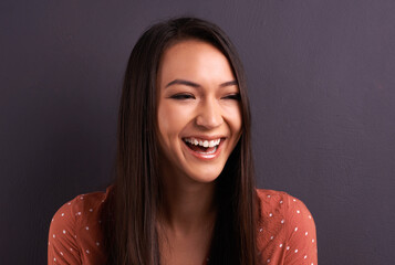 Woman, laughing and comedy humor in studio with carefree happiness, grey background or mockup...