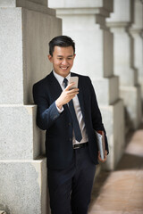 Asian business Man using his Smart phone outdoors.