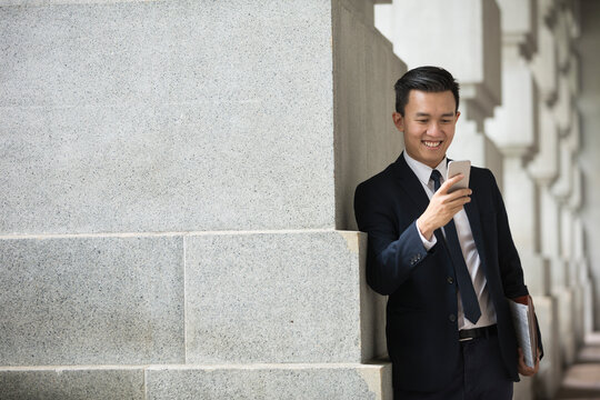 Asian business Man using his Smart phone outdoors.
