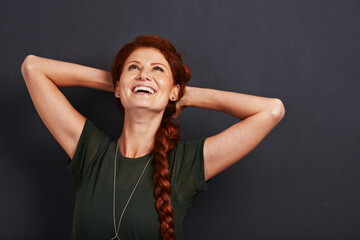 Happy woman, red hair and laughter in studio with positivity, excited and care free isolated on...