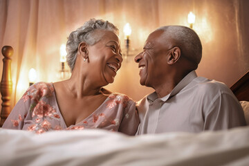 An elderly dark-skinned man and woman enjoying a moment of closeness as they lay together on a bed, expressing love and romance