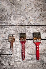 vertical several brushes on a craftsman's table with white paint - handicraft concept