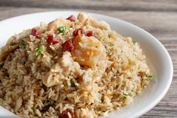A closeup view of a plate of fried rice, featuring shrimp, chicken and pork.
