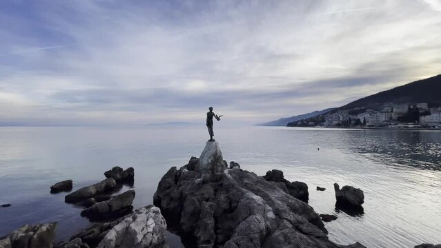 Statue of a woman on sea shore Resort town island in distance  wide Lovran, Opatija, Croatia