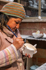 latina woman artisan painting plaster sculptures - working concept