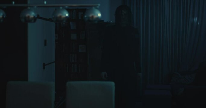 Horror scene - a dark and ominous demon walks through a ghastly living room at night