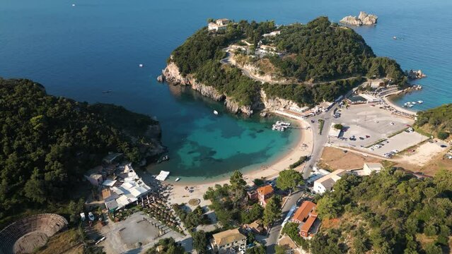Slow drone descend over sandy cove with boats docked on shore at Corfu Greece