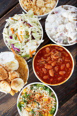 A top down view of BBQ meat sides, featuring baked beans, potato salad, and coleslaw.