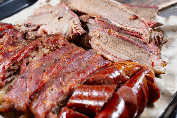 A closeup view of a tray of brisket, hot links and spare ribs.