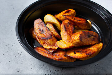 A view a black container of sliced roasted plantains.