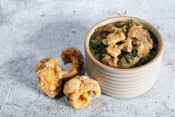 Close up of a bowl of tasty pork and spinach mungo served with pork crisps. 