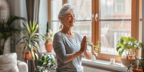 happy mature aged woman doing yoga in living room at home