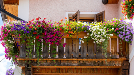 Traditional flowered balcony at the Alps and Dolomites. Colorful flowers on balcony. Summer time....