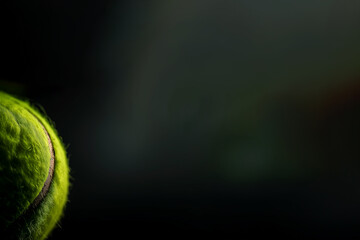 Tennis, sport avec raquette et balle. Balle de tennis jaune en plan rapproché sur un fond noir...