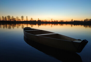wooden boat on a big beautiful lake at sunset.