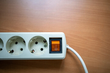 A power white strip or extension block power plugs with cable on wooden table
