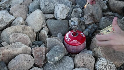 Person lighting a gas stove using matches while wildcamping, close up shot.