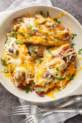 Baked chicken breasts with sauteed mushrooms, crispy bacon, melted cheddar and Monterey Jack cheese, honey mustard sauce closeup in the baking dish on the table. Vertical top view from above