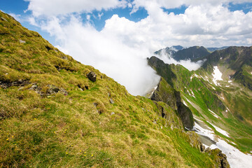 landscape of transylvania alps in summer. spots of snow among grass on the rocky slopes of fagaras range beneath a sky with clouds. popular travel destination in the mountains of romania