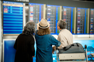 Group of travelers checking flight information at the flight information board. focus on a woman pointing at flight